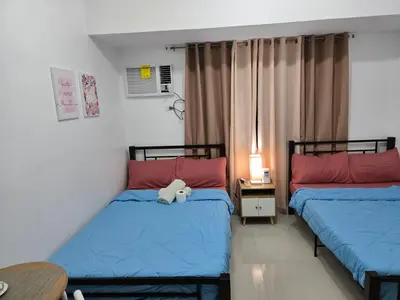 two beds in a room with a teddy bear between them at Staycation near US Embassy in Manila