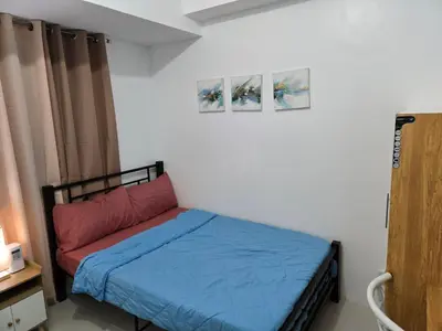 a small bed in a room with two pictures on the wall at Staycation near US Embassy in Manila