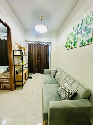 a living room with a green couch and a bedroom at Cozy Hearth Loft at Shore 3 in Manila