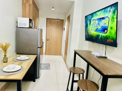 a kitchen with two tables and a television on a wall at Cozy Hearth Loft at Shore 3 in Manila
