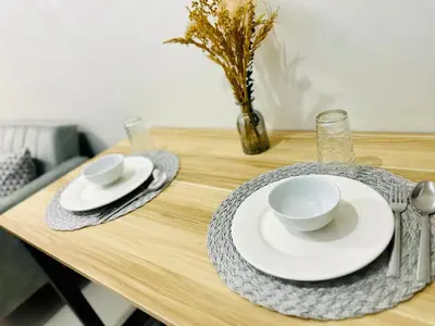 a table with white plates and bowls and a vase at Cozy Hearth Loft at Shore 3 in Manila
