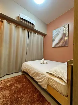 a bedroom with a bed with a television on the wall at Cozy orange room at shore in Manila