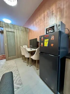 a room with a refrigerator and a table with chairs at Cozy orange room at shore in Manila