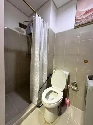 a small bathroom with a toilet and a shower at Cozy orange room at shore in Manila