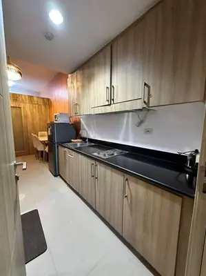 a kitchen with wooden cabinets and a black counter top at Cozy orange room at shore in Manila