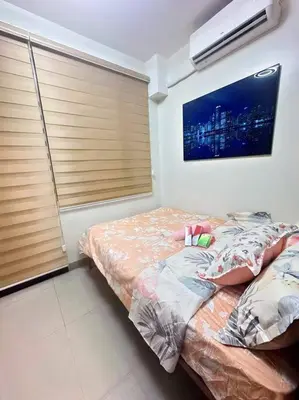 a bedroom with two beds and a tv on the wall at Nalin house SHORE 2 Residences in Manila