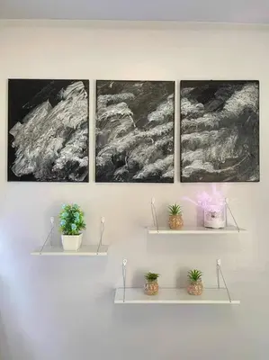 a shelf with three pictures and potted plants on it at Shore Residences Staycation by K in Manila