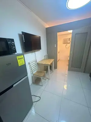 a kitchen with a refrigerator and a table with a microwave at Cozy shore 1 residences in Manila