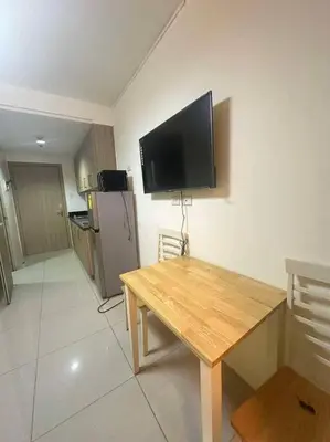 a kitchen with a table and a television on the wall at Cozy shore 1 residences in Manila