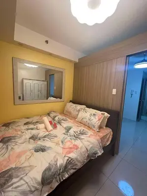 a woman laying on a bed in a bedroom at Cozy shore 1 residences in Manila