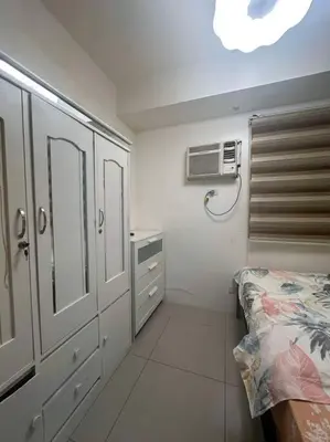 a bedroom with a bed and a air conditioner at Cozy shore 1 residences in Manila