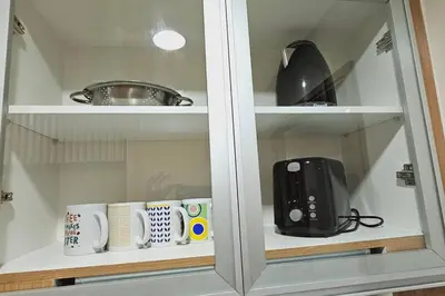 a kitchen cabinet with cups and utensils in it at 1BR self-contained CONDO in Makati with amenities! in Manila