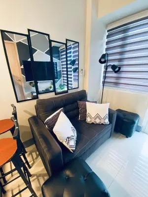 a living room with a black couch and a table at Jazz Cozy Abode in Manila