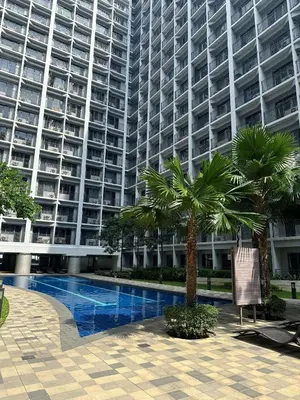 a large apartment building with a swimming pool and palm trees at Casa Antonietta at Shores Residences in Manila
