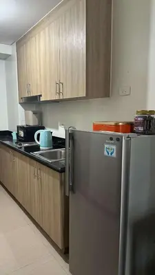 a kitchen with a stainless steel refrigerator and wooden cabinets at Casa Antonietta at Shores Residences in Manila