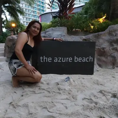 a woman sitting in the sand next to a sign at Azure Urban Dream Staycation in Manila