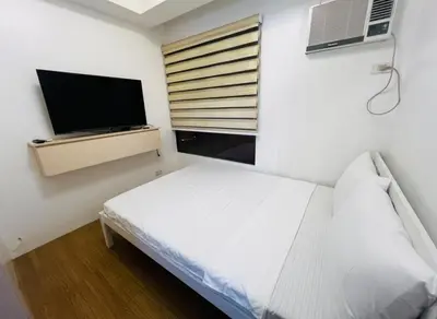 a bedroom with a bed and a flat screen tv at Porto Vita Towers in Manila