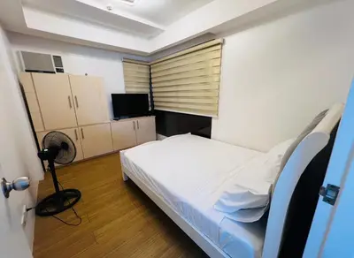 a small bedroom with a bed and a television at Porto Vita Towers in Manila
