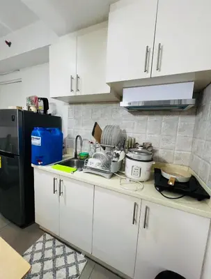 a kitchen with white cabinets and a black refrigerator at Porto Vita Towers in Manila