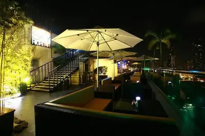 a restaurant with an umbrella and a pool at night at Budget Accommodation at Ace Suites by the Famous Indoor Water Spa in Manila