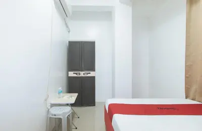 a room with two beds and a table and a refrigerator at RedDoorz at Najar Residences near NAIA Terminal in Manila