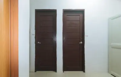 three brown doors in a room with white walls at RedDoorz at Najar Residences near NAIA Terminal in Manila