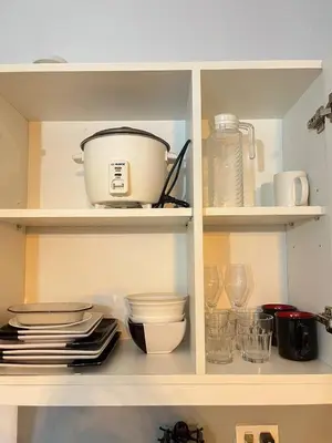 a kitchen cabinet with dishes and a pot and plates at Alphas Haven in Manila