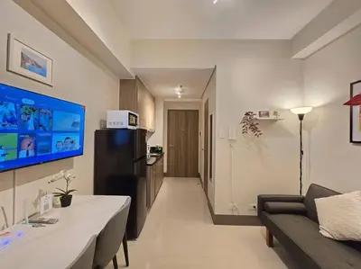a living room with a couch and a refrigerator at 1BR Condotel with Balcony at FAME Residences #FM58 in Manila