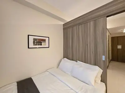 a bedroom with a bed with white sheets and pillows at 1BR Condotel with Balcony at FAME Residences #FM60 in Manila