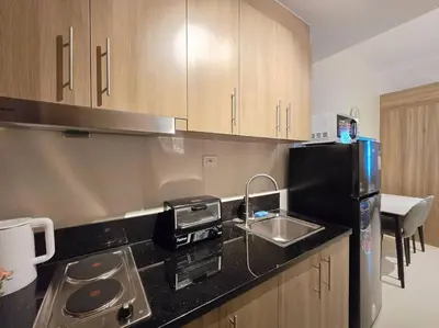 a kitchen with a sink and a black refrigerator at 1BR Condotel with Balcony at FAME Residences #FM60 in Manila