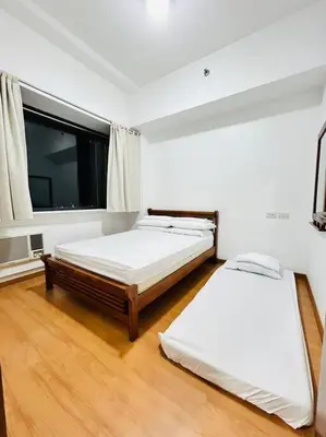 two beds in a room with a large window at Budget Twin-1Bedroom at Ace Suites in Manila