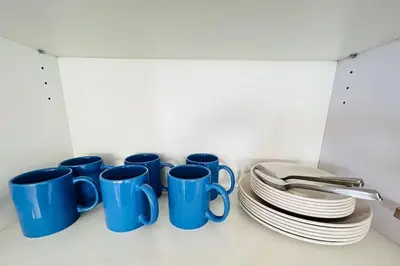 a row of blue coffee mugs and plates on a shelf at Budget Twin-1Bedroom at Ace Suites in Manila