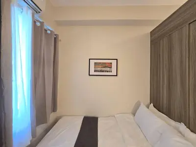 a bedroom with a white bed with a window at 1BR Condotel with Balcony at FAME Residences #FM61 in Manila