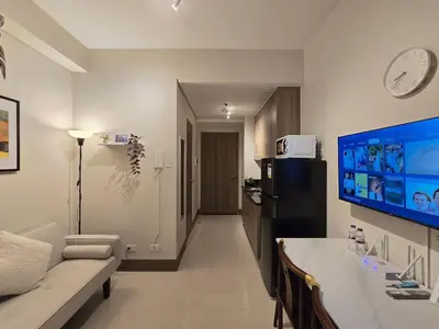 a living room with a couch and a tv on the wall at 1BR Condotel with Balcony at FAME Residences #FM61 in Manila
