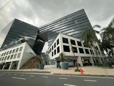 a building on a street with palm trees in front of it at Shore Family Suite 2 Beds WiFi TV Netflix Near MOA 9120 in Manila