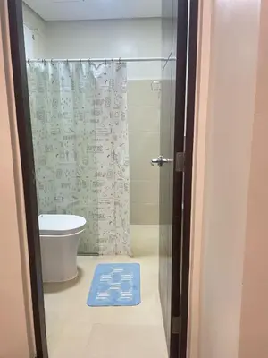 a bathroom with a toilet and a shower with a blue mat at Angsana Breeze at Paseo Verde Las Piñas in Manila