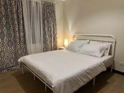 a bed with white sheets and pillows in a bedroom at Angsana Breeze at Paseo Verde Las Piñas in Manila