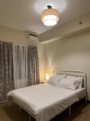 a bedroom with a white bed with a lamp at Angsana Breeze at Paseo Verde Las Piñas in Manila