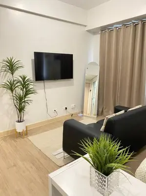 a living room with a couch and a flat screen tv at SMDC Park Residences near SM City Sta Rosa unit 1 in Ibaba
