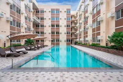 a swimming pool in a building with chairs and an umbrella at Cozy Unit Right by the Pool with Massage in Silang