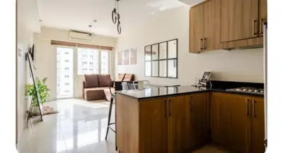a kitchen with wooden cabinets and a living room at Sosyal Staycation , Pasay City Shore Residences Tower D Sunrise Drive Mall of Asia Complex Pasay City Philippines SMDC SHORE 1 RESIDENCES Pasay City in Manila