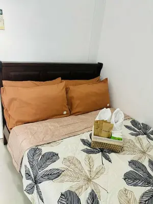 a bedroom with a bed with a bedspread with towels and a basket at Affordable Staycation At Sea Residence Near Moa By Dona Flores in Manila