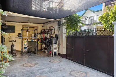 a garage with a black gate and a balcony at Cozy Las Pinas Haven with Big Garden, Pet Friendly - Near Super Market and the Airport in Manila