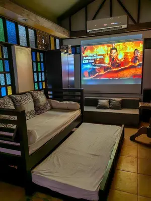 a room with two beds and a large screen at Cozy Las Pinas Haven with Big Garden, Pet Friendly - Near Super Market and the Airport in Manila