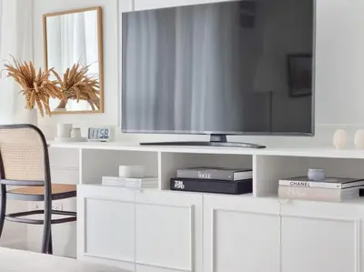 a white entertainment center with a tv and a chair at King Bed, Washer, Air Dry, Sauna, Gym & Pool Access, FAST Wi-Fi, Elegant Studio, Near Venice Grand Canal Mall, Walking Distance Britsh Embassy, 5 min drive to BGC, 10 min drive to Manila Airport NAIA 3 in Manila