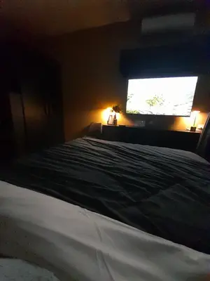 a bedroom with a bed and a large television at South Residences, Las Piñas in Manila