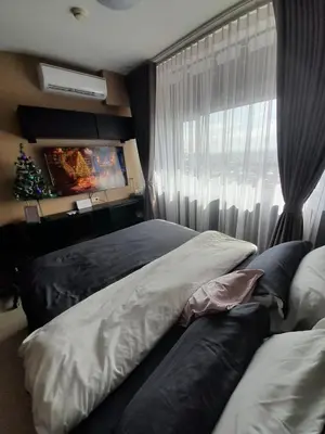 a bedroom with two beds and a window with a christmas tree at South Residences, Las Piñas in Manila