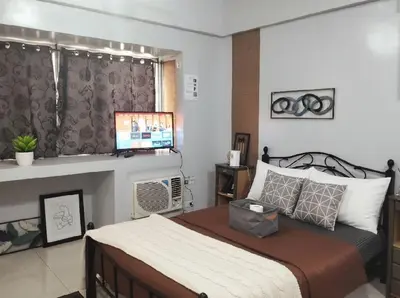 a bedroom with a bed and a flat screen tv at Heart of BGC in Manila