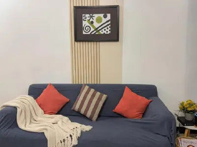 a blue couch with pillows and a clock on the wall at Heart of BGC in Manila