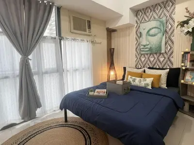 a bedroom with a blue bed and a window at Heart of BGC in Manila